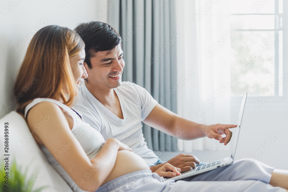 Young Asian couple using laptop for buying/shopping items to prepare to their baby Young Asian couple using laptop for buying/shopping items to prepare to their baby