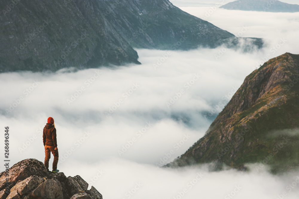 Traveler on cliff overlooking mountain clouds alone hiking adventure journey outdoor Norway vacations traveling lifestyle weekend getaway