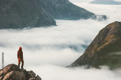 Traveler on cliff overlooking mountain clouds alone hiking adventure journey outdoor Norway vacations traveling lifestyle weekend getaway © EVERST