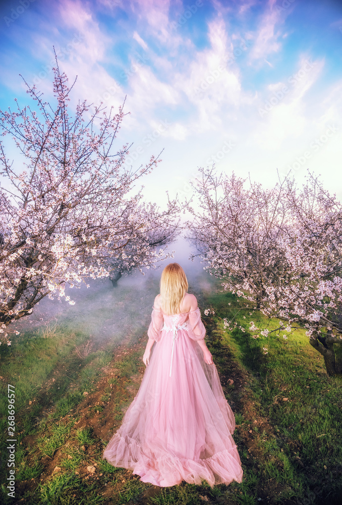 Sevastopol, Republic of Crimea - April 1, 2019: A girl in a beautiful pink dress among flowering almond branches 