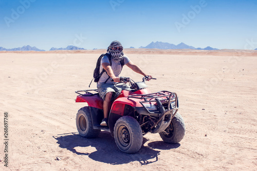 A group of quad bikes drive in the desert