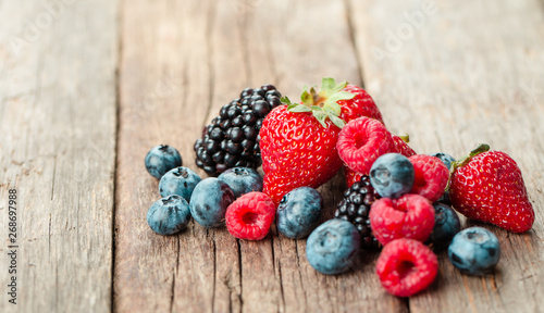Fresh Summer Berries mix with Strawberry, Raspberry, Red currant, Blueberry and Blackberry on wood background.
