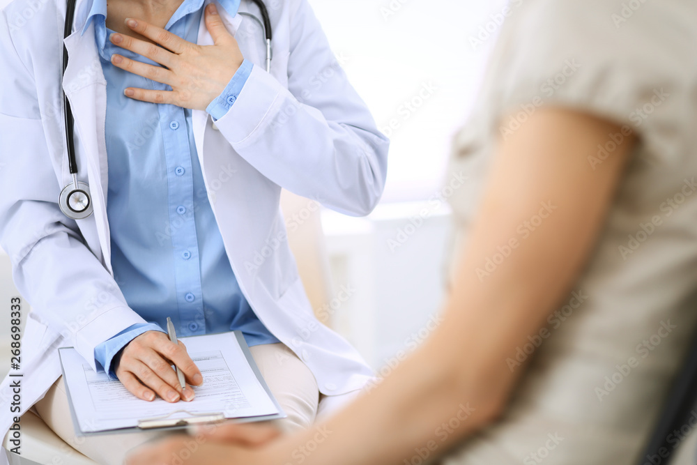 Doctor and patient talking. Physician at work in hospital while writing up medication history records form on clipboard near sitting woman. Healthcare and medicine concepts Doctor and patient talking. Physician at work in hospital while writing up medication history records form on clipboard near sitting woman. Healthcare and medicine concepts