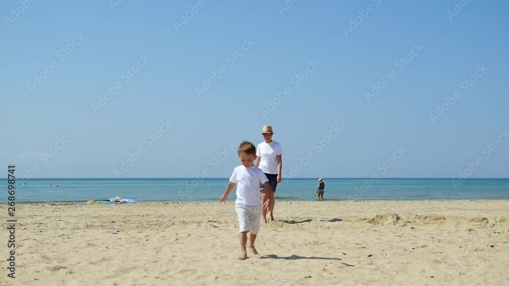 Mom and child walk along the sandy beach of the sea, on a sunny day Mom and child walk along the sandy beach of the sea, on a sunny day