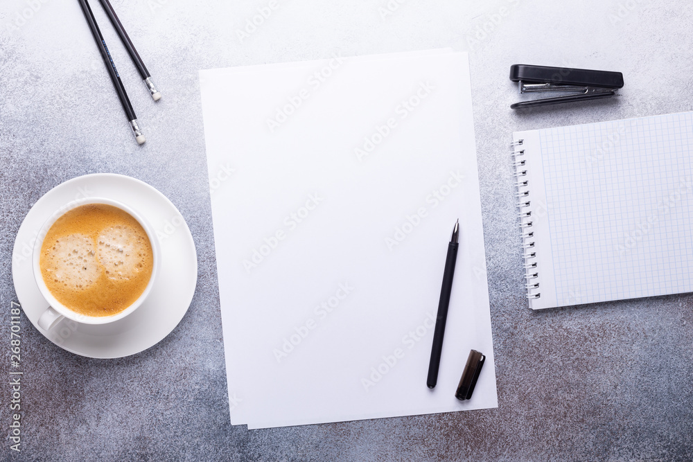 Office workplace with blank paper, cup of coffee, note pad and pen. Stone background. Top view Office workplace with blank paper, cup of coffee, note pad and pen. Stone background. Top view