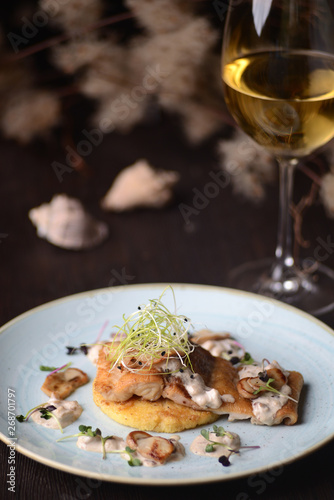 fried fish fillet with a sauce on the background of a glass of wine