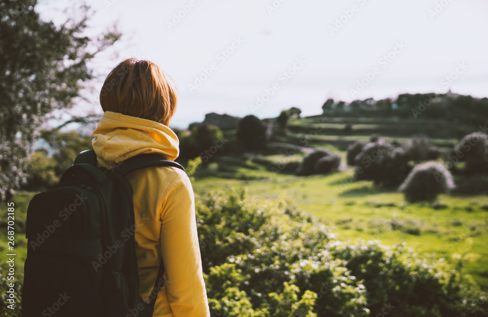 tourist traveler with yellow backpack standing on green top on mountain, hiker view from back looking on hills, girl enjoying nature panoramic landscape in trip, relax holiday concept