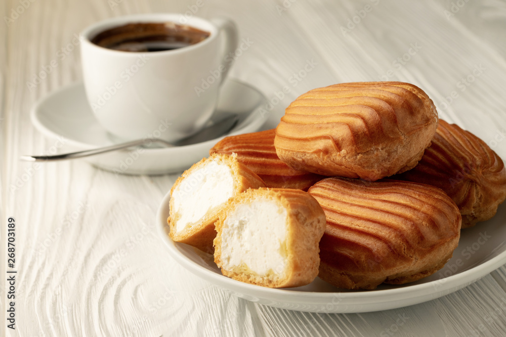 Plate with profiteroles and a cup of coffee in the background Plate with profiteroles and a cup of coffee in the background