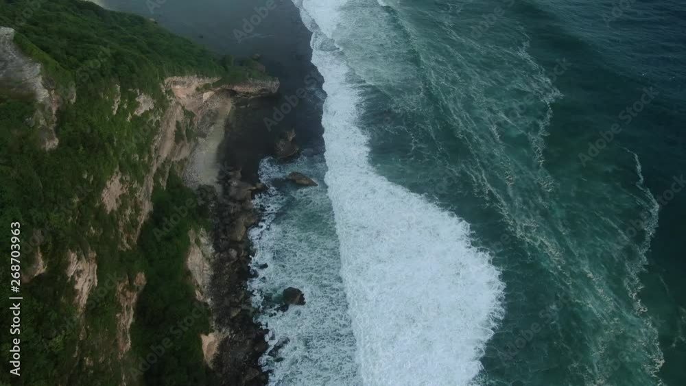 Aerial view of green cliff and blue ocean with breaking waves Bali, Indonesia Aerial view of green cliff and blue ocean with breaking waves Bali, Indonesia
