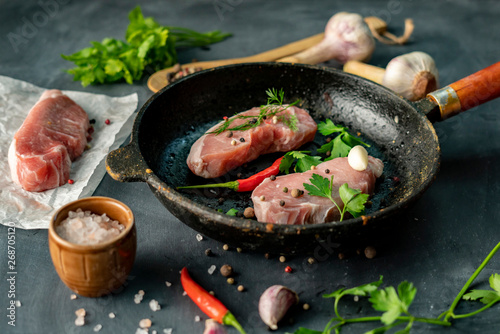 raw pork slices or steaks in a hot frying pan at the kitchen , rustic photo style witj ingredient
