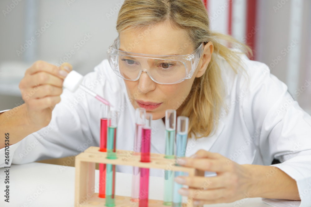 mature female researcher using a pipette in lab mature female researcher using a pipette in lab