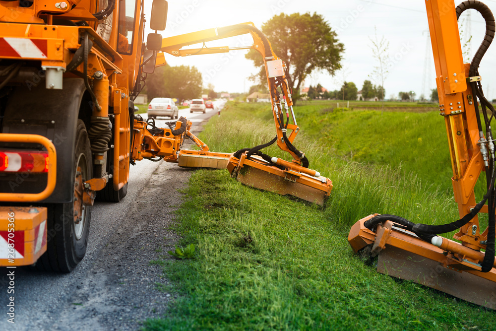 Professional industrial machine cutting grass by the road for