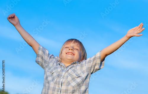 Happy boy with arms raised to the sky