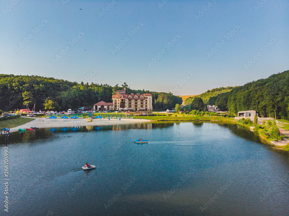 Fototapeta premium aerial view of resort near lake forest around. people on boats and catamarans