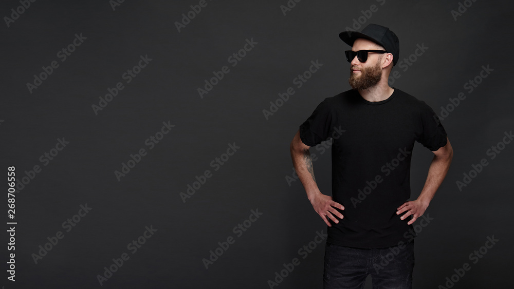 Hipster handsome male model with beard wearing black blank t-shirt with space for your logo or design in casual urban style wth copy space Hipster handsome male model with beard wearing black blank t-shirt with space for your logo or design in casual urban style wth copy space