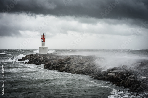 grosse tempête sur un quai et un phare 