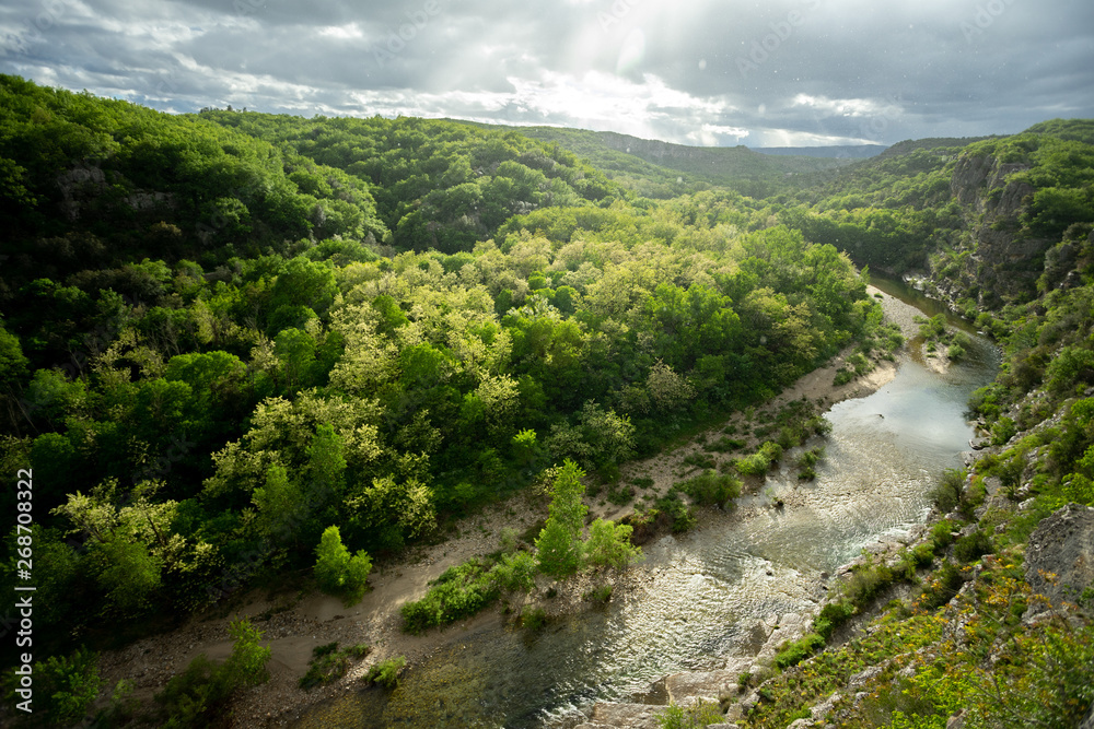 vue sur les gorges d'une rivière bordée de forêt, sous la pluie vue sur les gorges d'une rivière bordée de forêt, sous la pluie