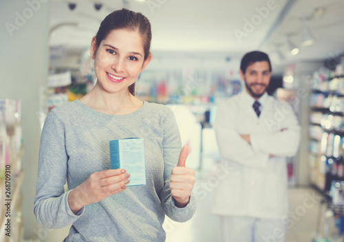 Smiling female client is satisfied of recommended medicine in apothecary.