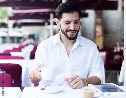 Man drinking coffee in summer cafeteria