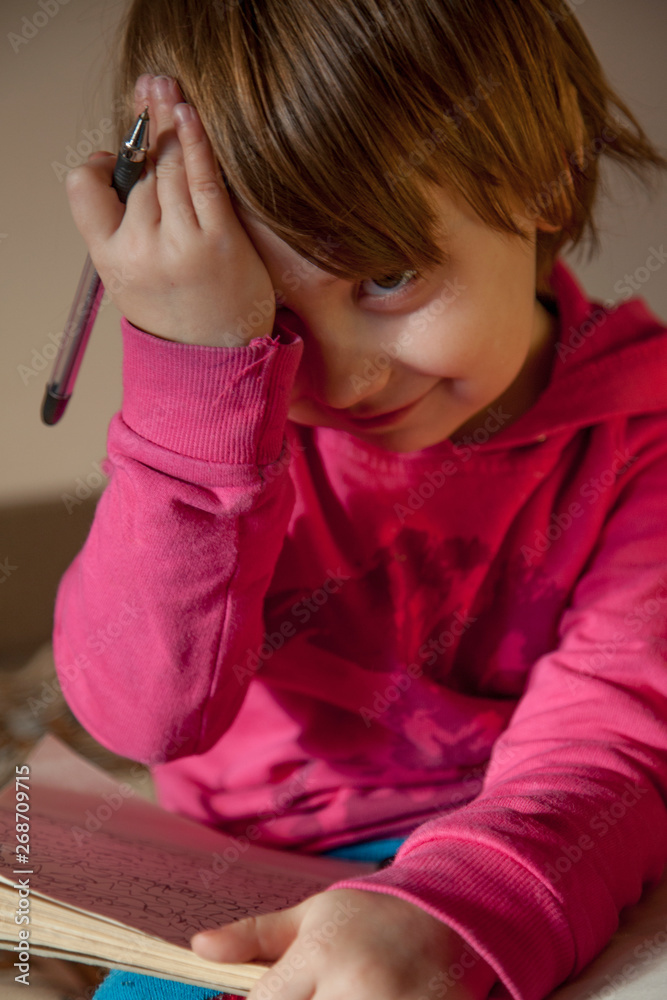 Difficult education concept. Portrait of beautiful little child girl holding notebook and penr. Humorous photo. Difficult education concept. Portrait of beautiful little child girl holding notebook and penr. Humorous photo.