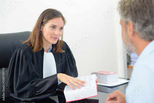 Photos female lawyer holding book in meeting with male client