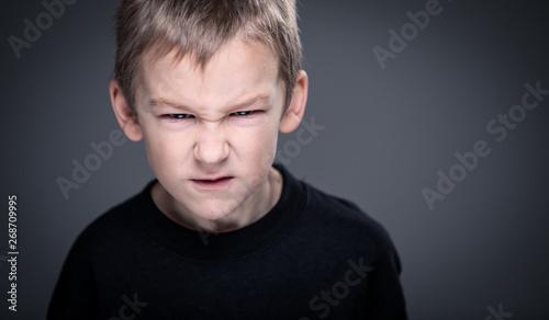 Loads of aggression in a little boy - education concept hinting behavioral problems in young children (shallow DOF) - little boy with hands clenched into fists about to punch someone