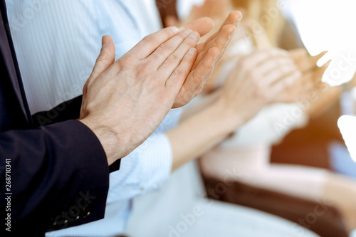 Business people clapping and applause at meeting or conference, close-up of hands. Group of unknown businessmen and women in modern white office. Success teamwork or corporate coaching concept