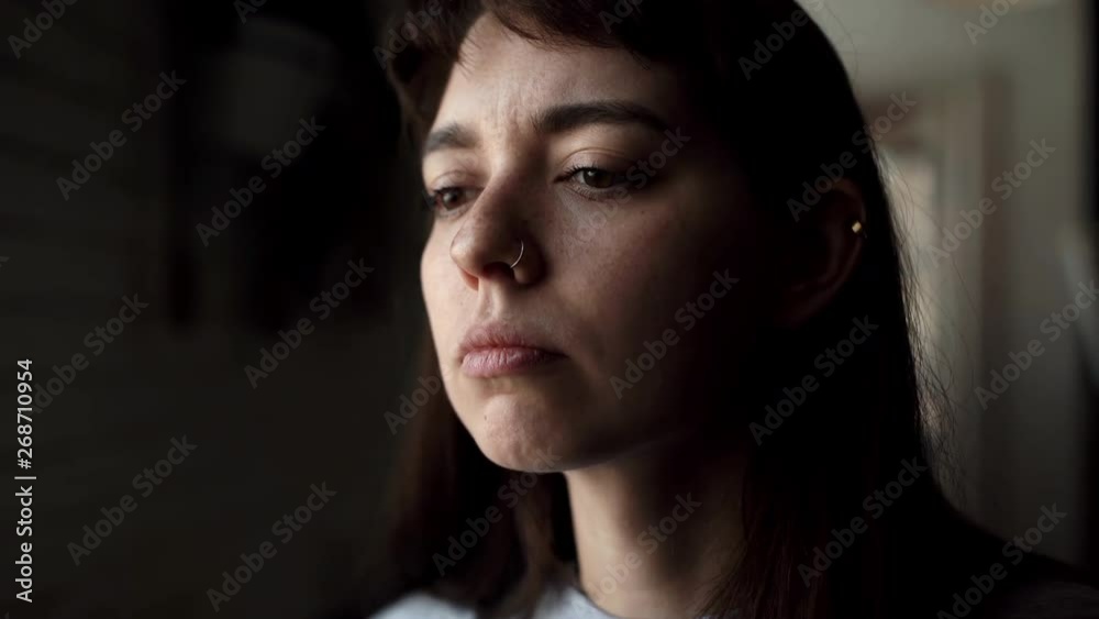 Girl with a ring in his nose is drinking coffee from a cup close-up in the cafe. Young woman enjoys a weekend or rest. Beautiful girl takes a sip of hot drink close-up