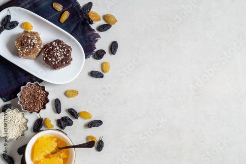 Healthy sweets made from natural ingredients on a white plate. Near honey, sesame and raisins