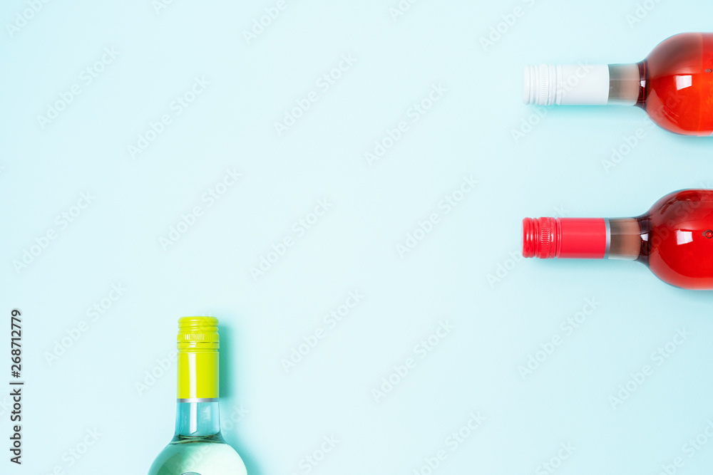 Layout frame of foil caps in different bright colors of white and rose wine bottles on blue background with copy space. Minimal abstract colorful mockup concept of alcohol beverage. Flat lay.