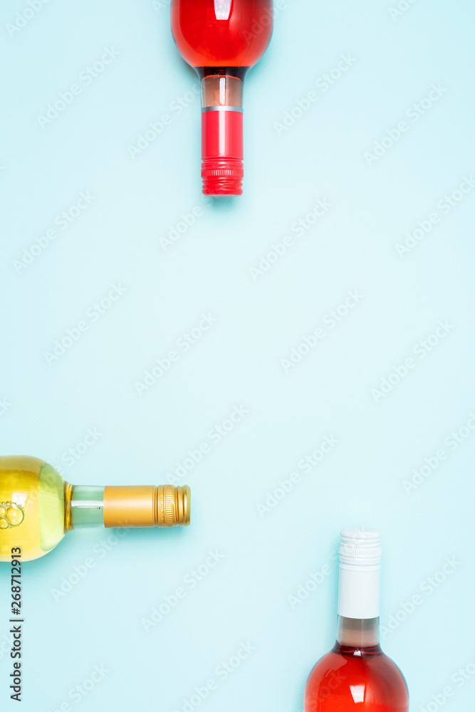 Layout frame of foil caps in different bright colors of white and rose wine bottles on blue background with copy space. Minimal abstract colorful mockup concept of alcohol beverage. Flat lay. Layout frame of foil caps in different bright colors of white and rose wine bottles on blue background with copy space. Minimal abstract colorful mockup concept of alcohol beverage. Flat lay.