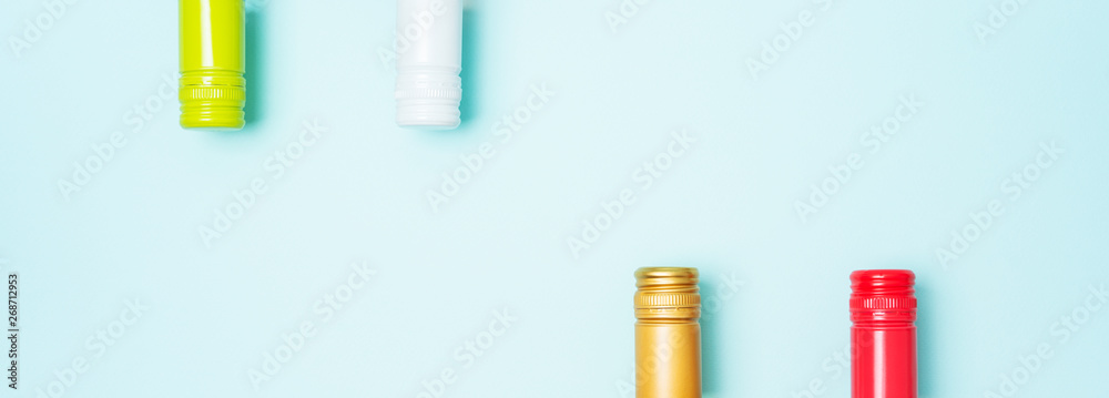 Colorful bottle caps of white and rose wine bottles on turquoise background. Minimal abstract colorful layout concept of summer time alcohol beverage. Long wide banner. Colorful bottle caps of white and rose wine bottles on turquoise background. Minimal abstract colorful layout concept of summer time alcohol beverage. Long wide banner.