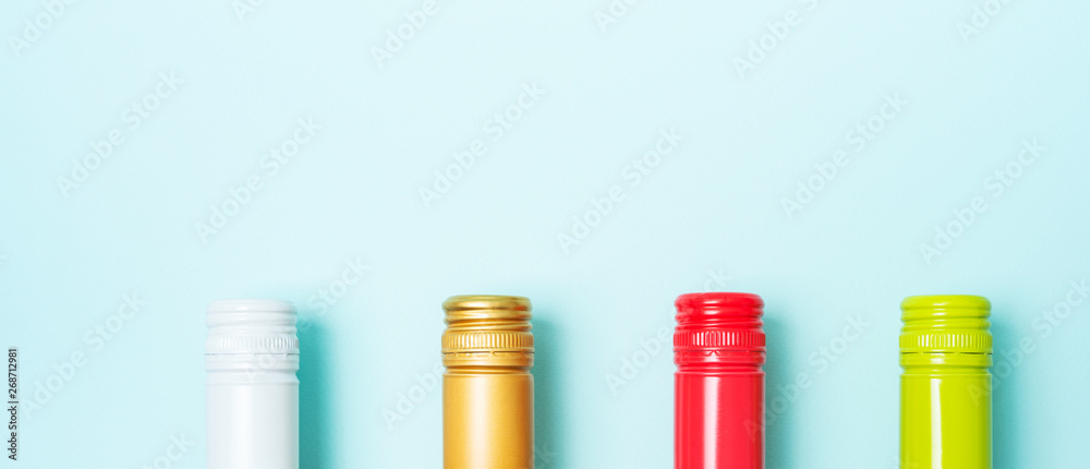 Screw bottle foil caps in different bright colors of white and rose wine bottles on blue background with copy space. Minimal abstract colorful mockup concept of alcohol beverage. Flat lay. Screw bottle foil caps in different bright colors of white and rose wine bottles on blue background with copy space. Minimal abstract colorful mockup concept of alcohol beverage. Flat lay.