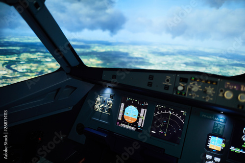Aircraft flight deck with radar meters and displays on control panel, cloudscape behind window, copy space