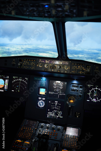 Nobody in flying plane on automatic: modern control panel with illuminated monitors and buttons, copy space