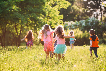 Large group of kids, friends boys and girls running in the park on sunny summer day in casual clothes .