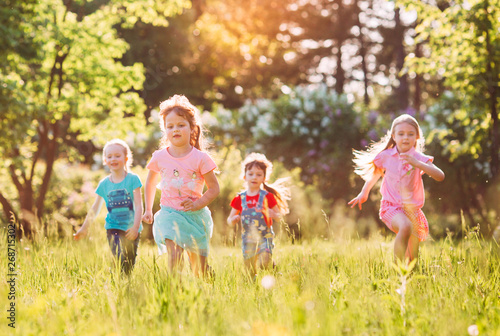 Large group of kids, friends boys and girls running in the park on sunny summer day in casual clothes .