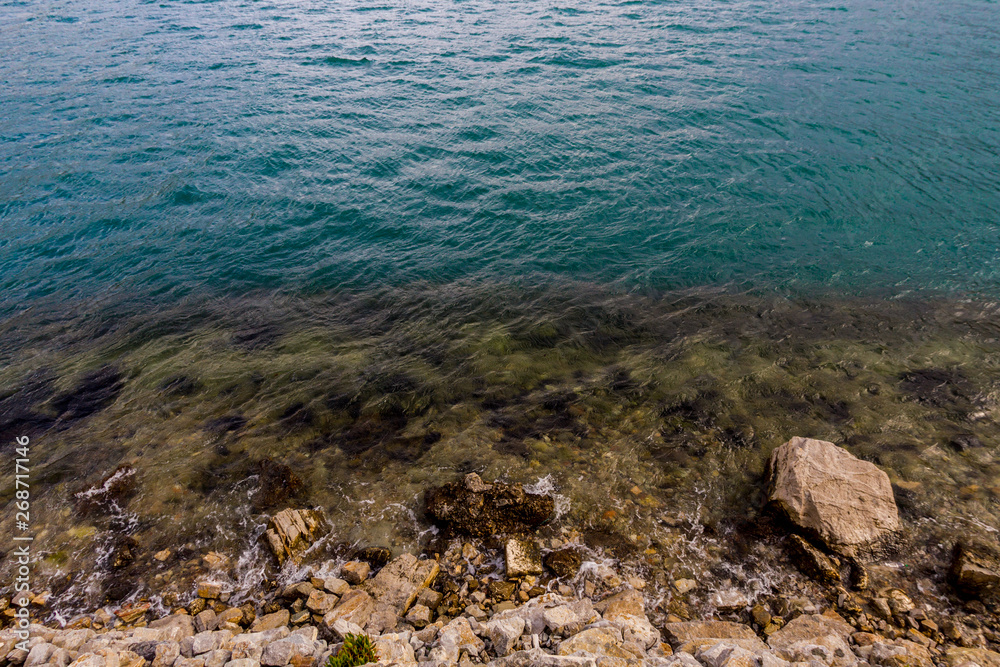 Blue sea surface with waves and rocky coast Blue sea surface with waves and rocky coast
