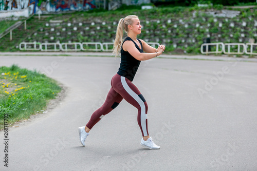 Fitness lifestyle. Young woman doing lunges in a jump. Workout at the stadium. Healthy life concept