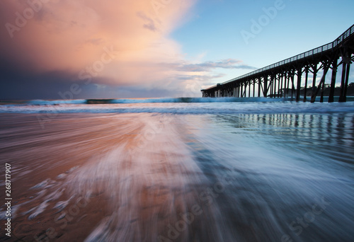 sunset on beach with pier during storm