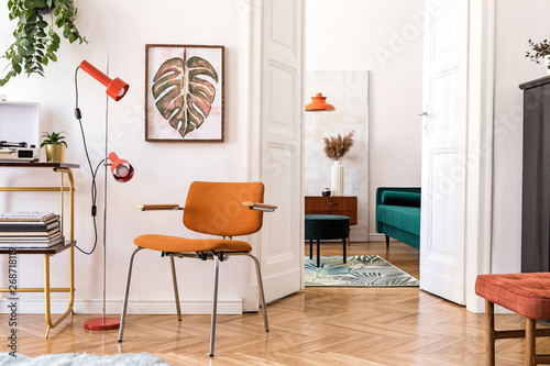 Stylish compositon of retro home interior with mock up poster frame, vintage orange chair, piano, furnitures, design lamps, gold shelf, plants and elegant accessories. Nice home decor of living room.  photo