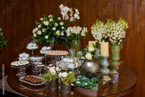 table with flowers, brazilian sweet , chocolate candy, party candy, condensed milk candy balls, chocolate truffles, brigadeiro, chocolate sprinkles, chocolate candy, sweets table