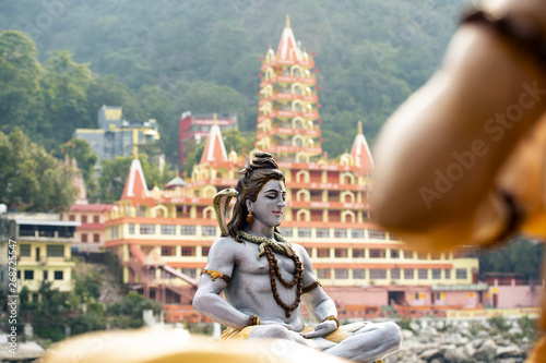 Photography (Selective focus) Stunning view of the statue of sitting Lord Shiva on the riverbank of the Ganges river