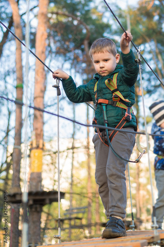 Little boy in a rope park. Active physical recreation of the child in the fresh air in the park. Training for children.