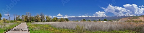 Jordan River Parkway Trail, Redwood Trailhead bordering the Legacy Parkway Trail, panorama views with surrounding trees and silt filled muddy water along the Rocky Mountains, Salt Lake City, Utah.  photo