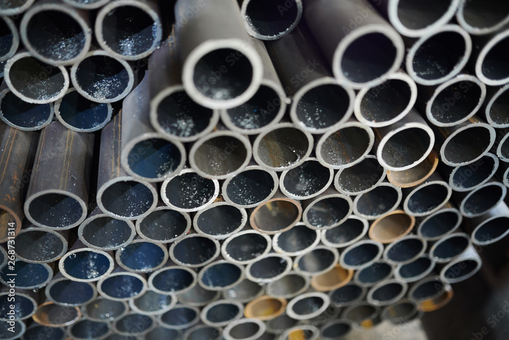 Background image of metal pipes stacked in warehouse of industrial plant, copy space
