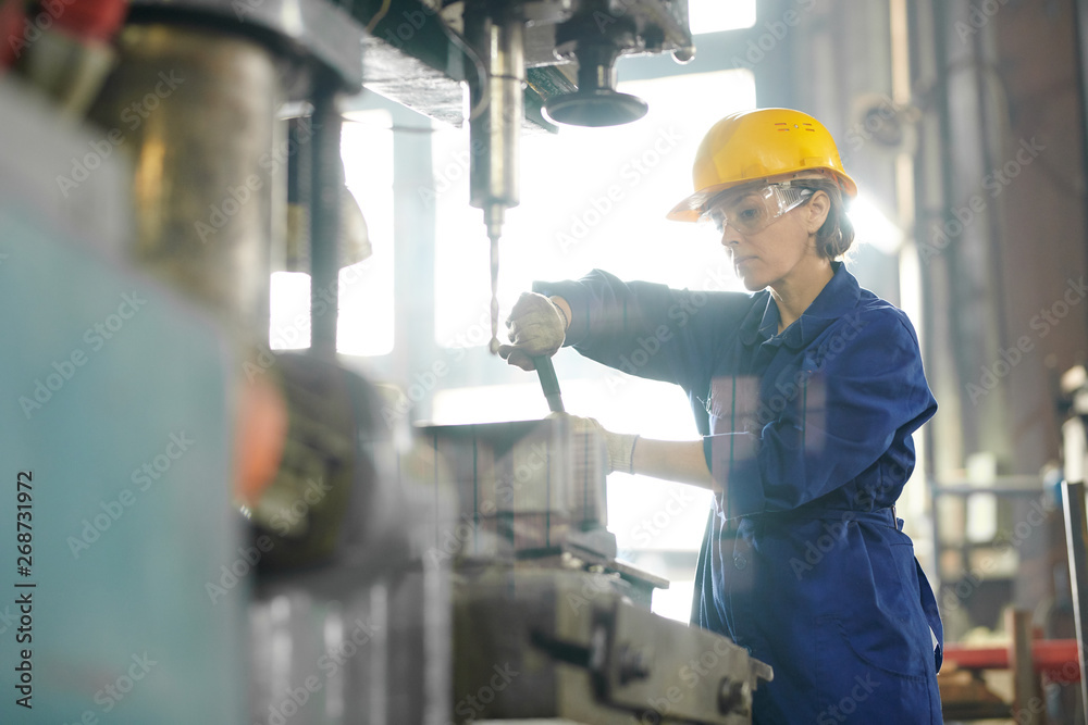Side view portrait of mature woman working at factory and repairing machine units, copy space Side view portrait of mature woman working at factory and repairing machine units, copy space