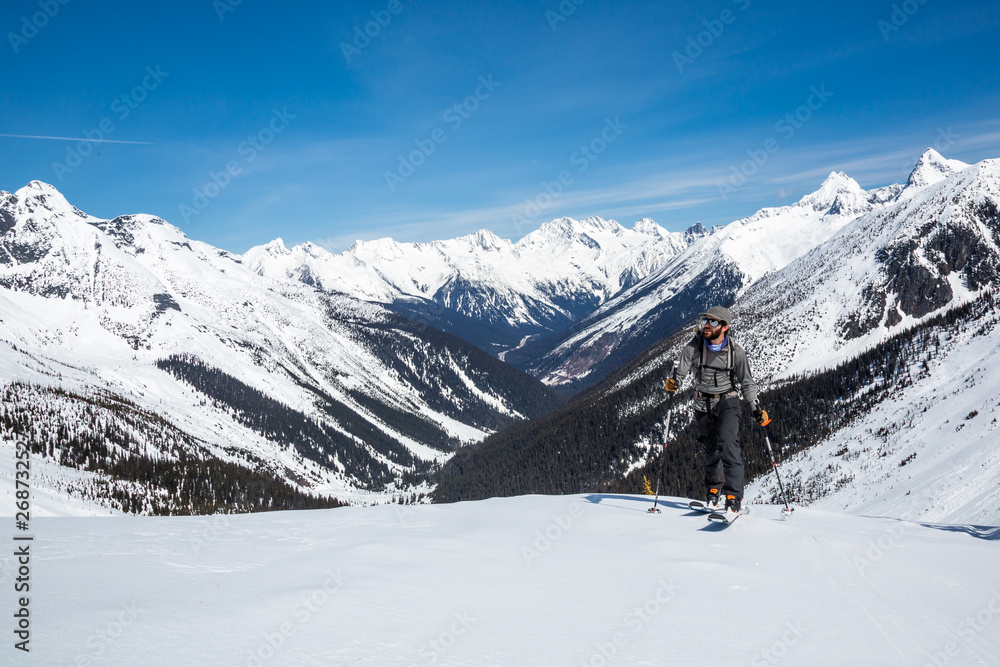 Man skins up the track toward the Asulkan Glacier and the Seven Steps to Paradise backcountry ski run. Behind him is the Trans-Canada Highway and Roger's Pass area