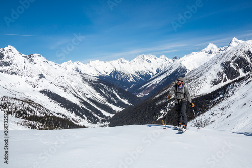Man skins up the track toward the Asulkan Glacier and the Seven Steps to Paradise backcountry ski run. Behind him is the Trans-Canada Highway and Roger's Pass area