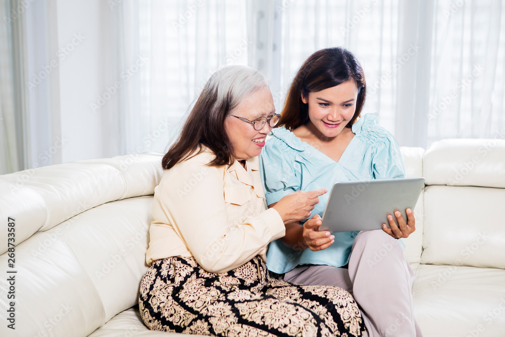 Old woman using a tablet with her daughter